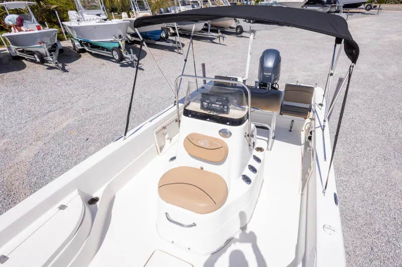 Slide: The Image of 2017 NauticStar 2400 Sport boat with canopy and seating, parked on gravel. - 32