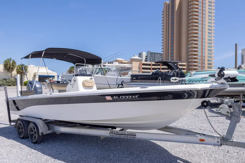 Slide: The Image of 2017 NauticStar 2400 Sport boat on trailer, parked near tall buildings. - 4