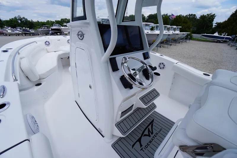 Slide: The Image of 2026 Tidewater 232 SS boat interior with steering wheel and seating, docked outdoors. - 29