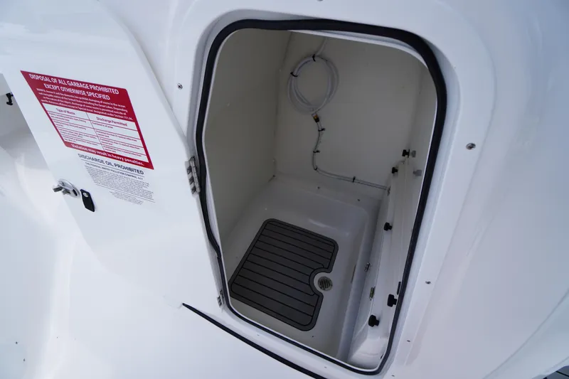 Slide: The Image of 2026 Tidewater 232 SS boat storage compartment with drainage and warning label. - 31