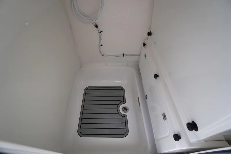 Slide: The Image of Interior compartment of 2026 Tidewater 232 SS boat, featuring a drain and storage space. - 32