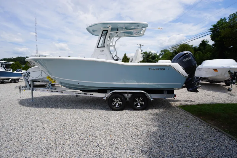 Slide: The Image of 2026 Tidewater 232 SS boat on trailer, parked on gravel lot under blue sky. - 85