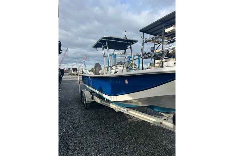 Slide: The Image of 2011 Carolina Skiff 258 DLV boat on trailer, blue hull, parked outdoors. - 3