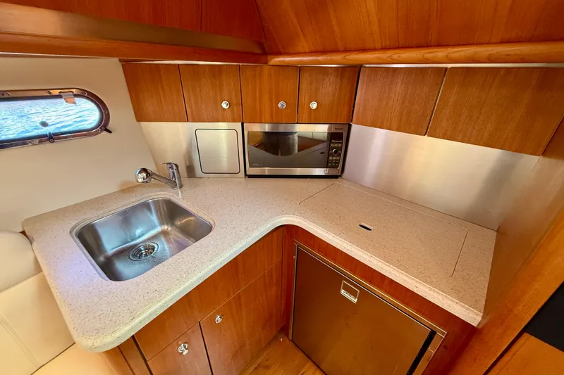 Slide: The Image of 2006 Tiara Yachts 3600 Sovran galley with sink, microwave, and wooden cabinetry. - 19