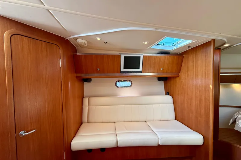 Slide: The Image of 2006 Tiara Yachts 3600 Sovran interior with white seating, wood paneling, and a mounted TV. - 6