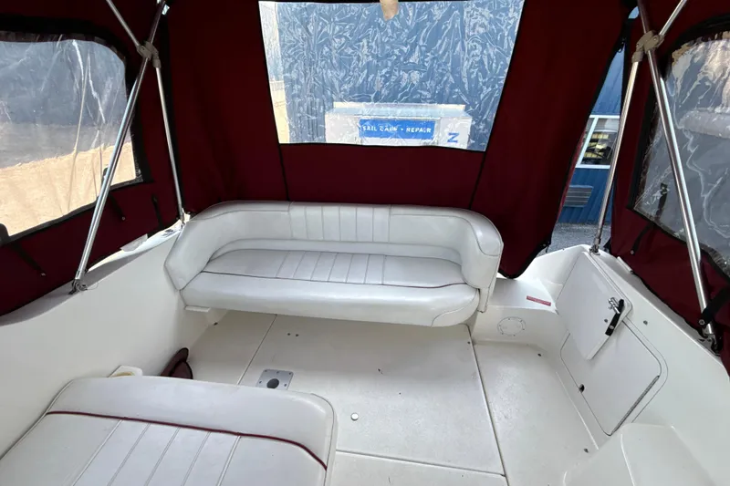 Slide: The Image of Interior of a 1996 Sea Ray 240 Sundancer boat with white seating and maroon canopy. - 20