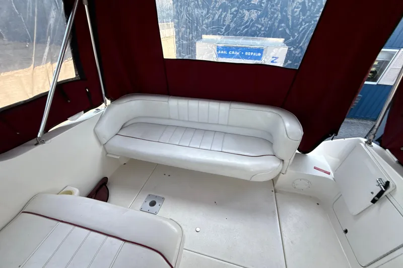 Slide: The Image of Interior of a 1996 Sea Ray 240 Sundancer boat with white seating and maroon canopy. - 23