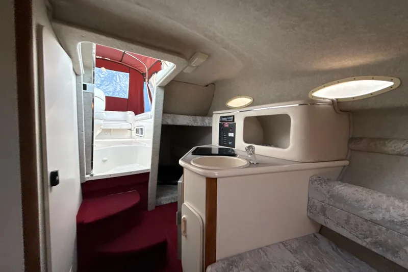 Slide: The Image of Interior of a 1996 Sea Ray 240 Sundancer boat, featuring a compact kitchenette and seating area. - 33