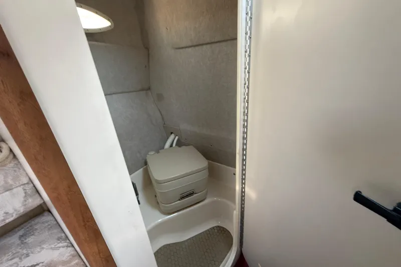 Slide: The Image of 1996 Sea Ray 240 Sundancer boat bathroom with compact toilet and light interior. - 34