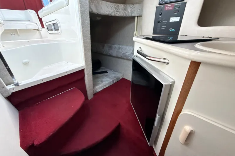 Slide: The Image of Interior of a 1996 Sea Ray 240 Sundancer boat with red carpet and compact kitchenette. - 35