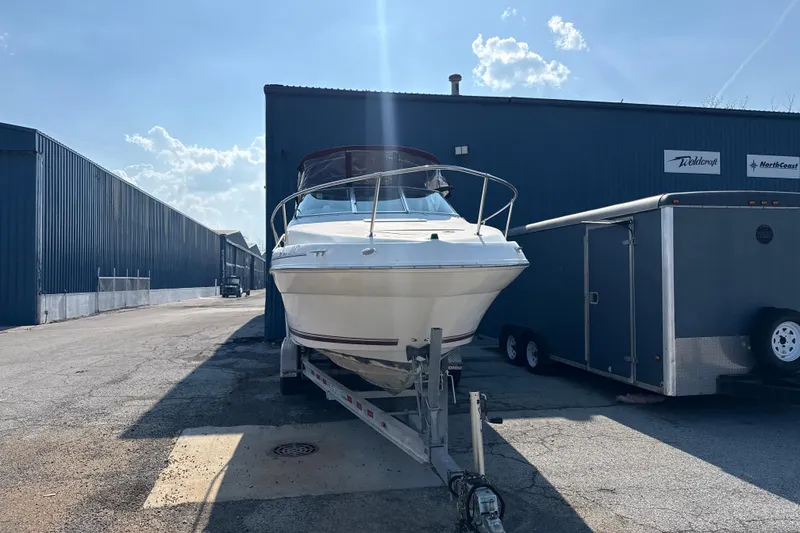 Slide: The Image of 1996 Sea Ray 240 Sundancer boat on trailer, parked outside industrial building. - 4