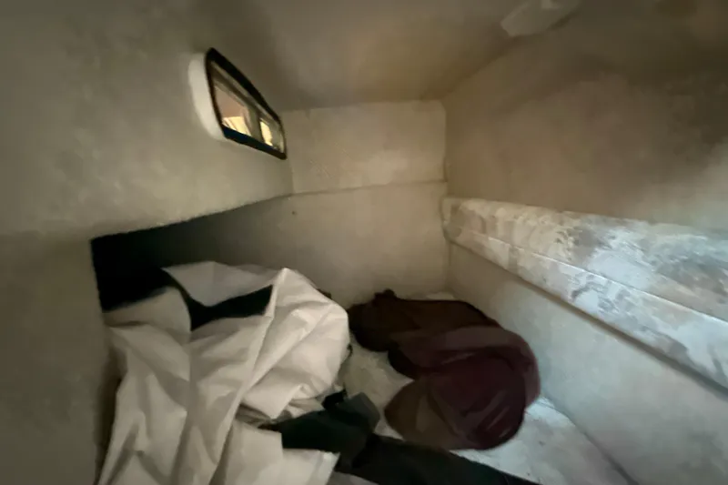 Slide: The Image of 1996 Sea Ray 240 Sundancer cabin interior with bedding and small window. - 44