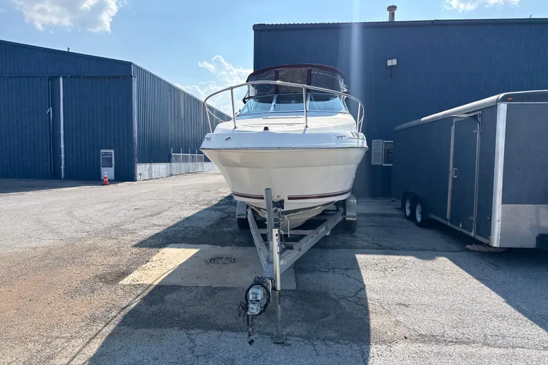 Slide: The Image of 1996 Sea Ray 240 Sundancer boat on trailer, parked beside a blue warehouse. - 5