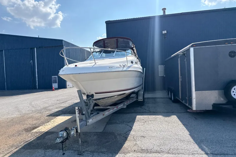 Slide: The Image of 1996 Sea Ray 240 Sundancer boat on trailer, parked beside a building under a clear sky. - 6