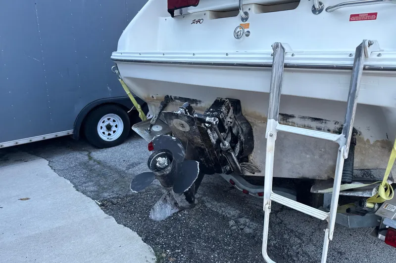 Slide: The Image of 1996 Sea Ray 240 Sundancer boat stern with propeller and ladder, parked on pavement. - 9