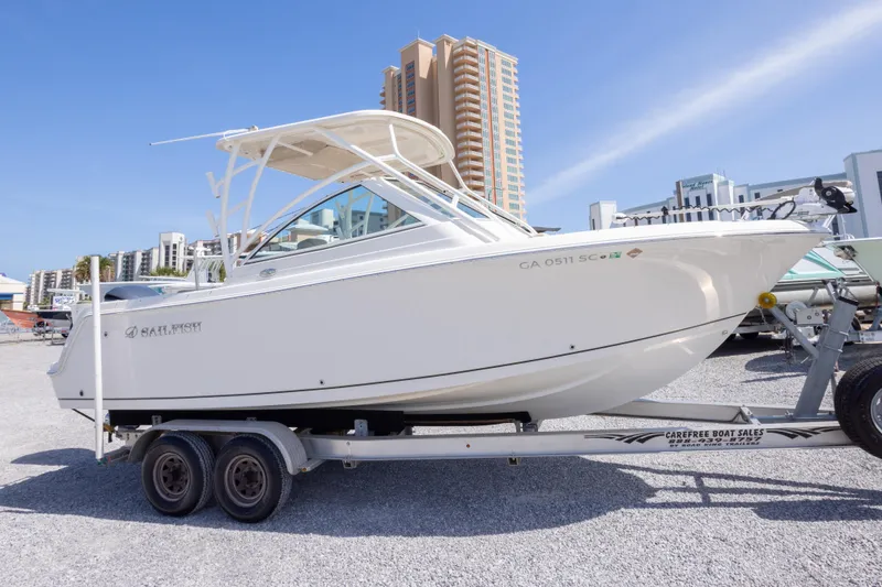 The Image of 2018 Sailfish 245 DC boat on trailer, displayed outdoors with buildings in the background. - 0