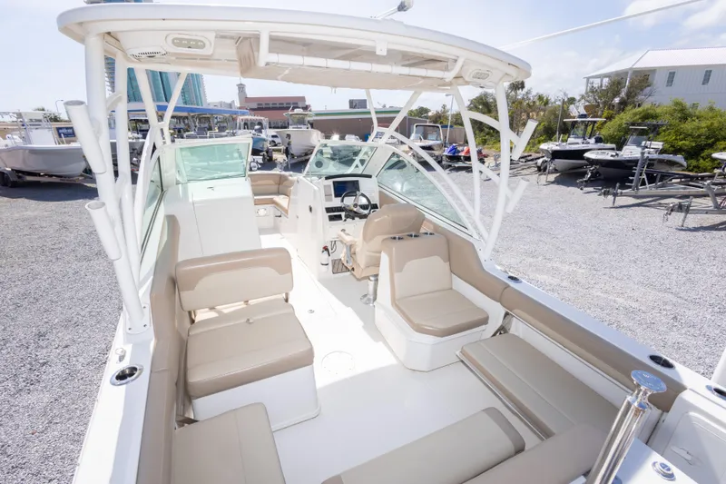 Slide: The Image of 2018 Sailfish 245 DC boat interior with beige seating, parked in a marina. - 19
