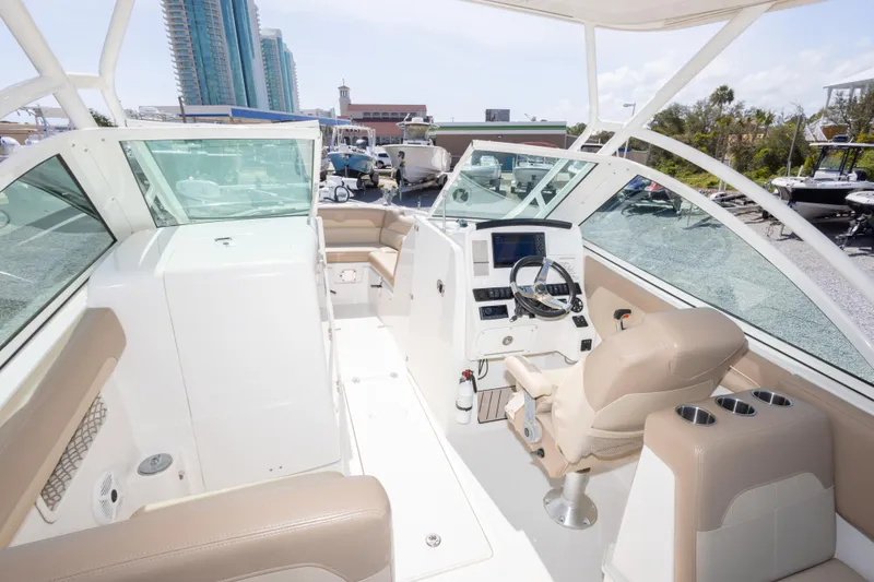 Slide: The Image of 2018 Sailfish 245 DC boat interior with beige seating and modern dashboard controls. - 21