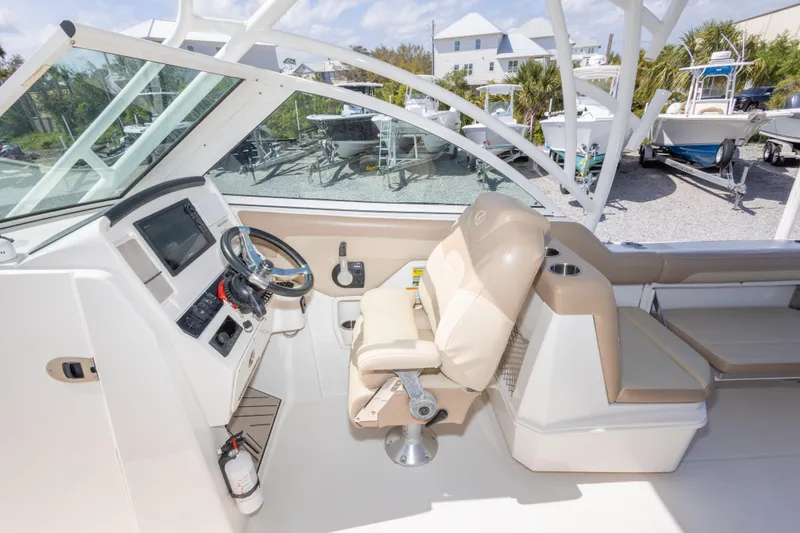 Slide: The Image of 2018 Sailfish 245 DC boat cockpit with steering wheel, beige seating, and control panel. - 24