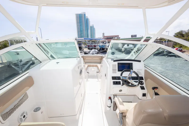 Slide: The Image of 2018 Sailfish 245 DC boat interior with modern dashboard and cityscape background. - 26