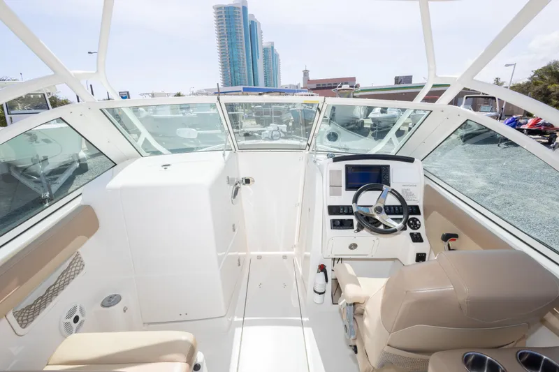 Slide: The Image of 2018 Sailfish 245 DC boat interior with modern helm, steering wheel, and beige seating. - 27