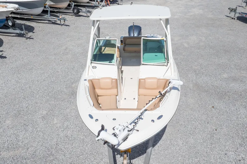 Slide: The Image of 2018 Sailfish 245 DC boat with tan seating, viewed from above, parked on gravel. - 43