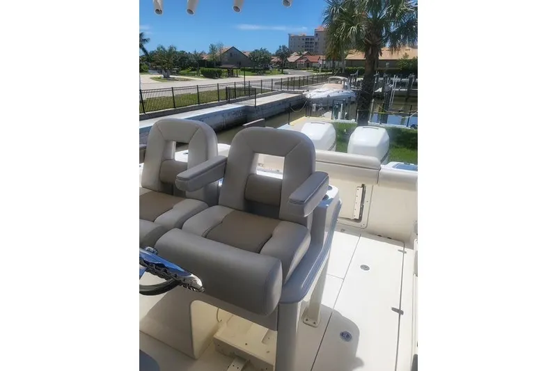 Slide: The Image of 2018 Boston Whaler 280 Outrage boat interior with plush seating and dual outboard motors. - 4