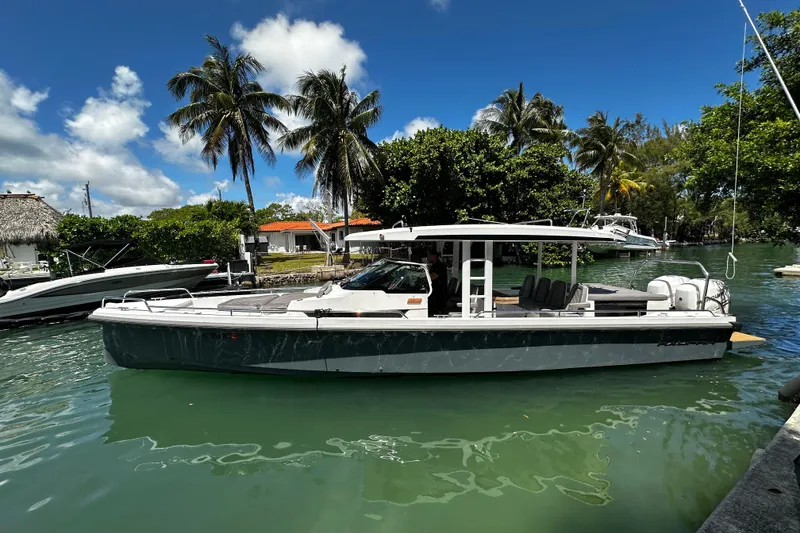 The Image of 2018 Axopar 37 Sun-Top boat docked in tropical marina with palm trees. - 0