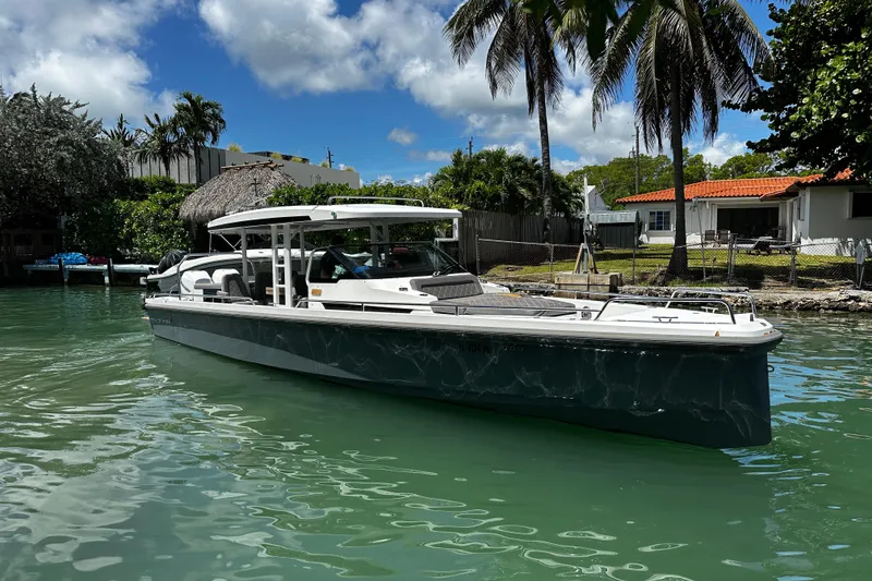 Slide: The Image of 2018 Axopar 37 Sun-Top boat on a sunny day, docked near tropical palm trees. - 11