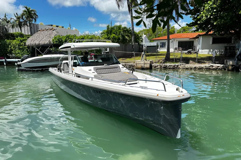 Slide: The Image of 2018 Axopar 37 Sun-Top boat docked in a serene, tropical waterfront setting. - 13