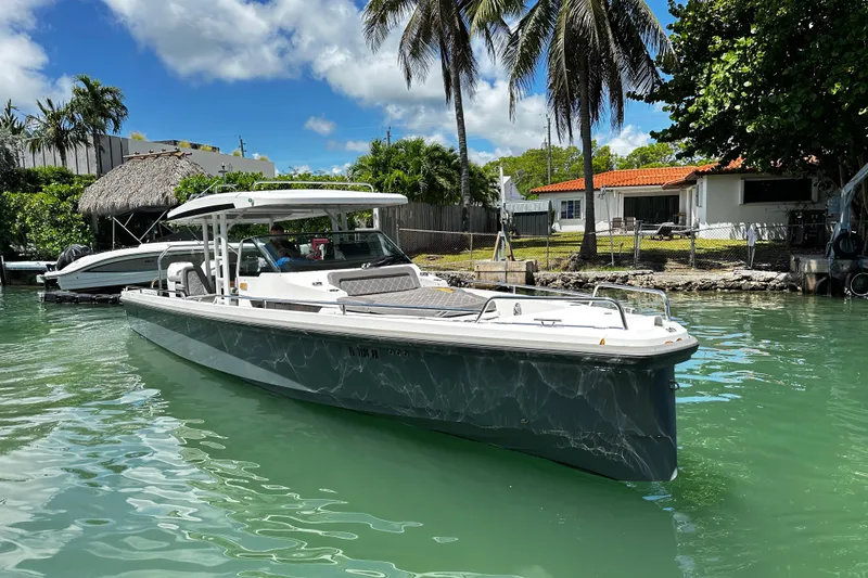 Slide: The Image of 2018 Axopar 37 Sun-Top boat docked in a tropical waterfront setting. - 2