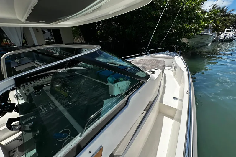 Slide: The Image of 2018 Axopar 37 Sun-Top boat docked by lush greenery and calm waters. - 24