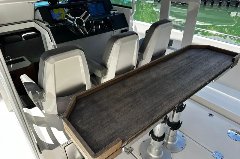 Slide: The Image of 2018 Axopar 37 Sun-Top boat interior with helm, seating, and wooden table. - 28