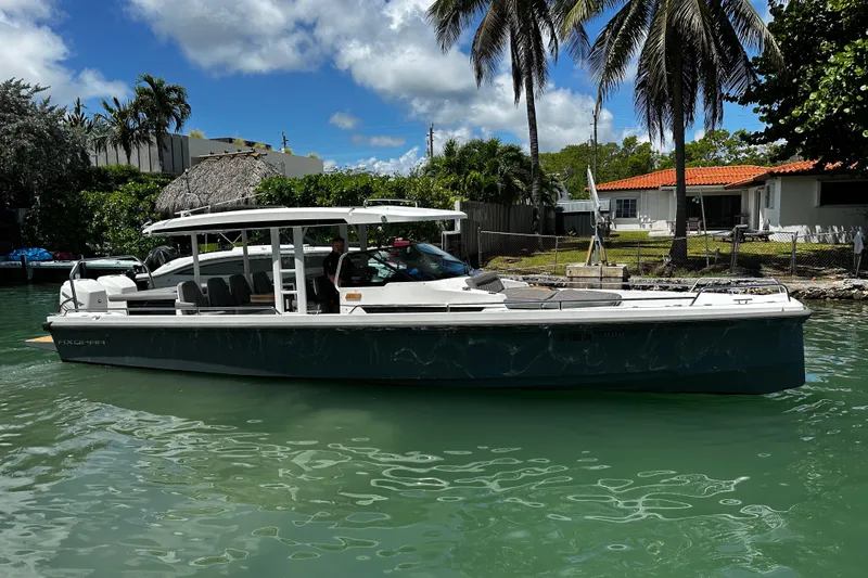 Slide: The Image of 2018 Axopar 37 Sun-Top boat on a sunny day, surrounded by palm trees and calm water. - 3