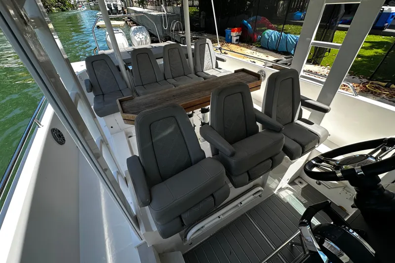 Slide: The Image of 2018 Axopar 37 Sun-Top boat interior with gray seating and wooden table. - 33