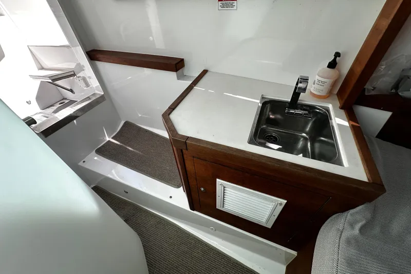 Slide: The Image of Interior of 2018 Axopar 37 Sun-Top featuring a compact sink and wooden cabinetry. - 38