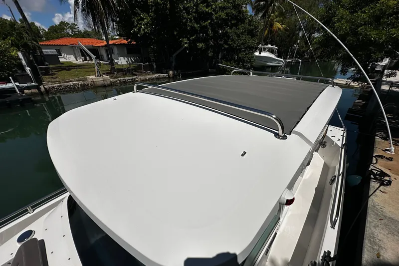 Slide: The Image of 2018 Axopar 37 Sun-Top boat docked by lush greenery and waterfront homes. - 43