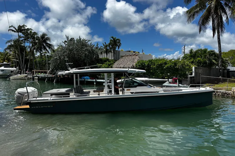 Slide: The Image of 2018 Axopar 37 Sun-Top boat docked in a tropical marina setting. - 9