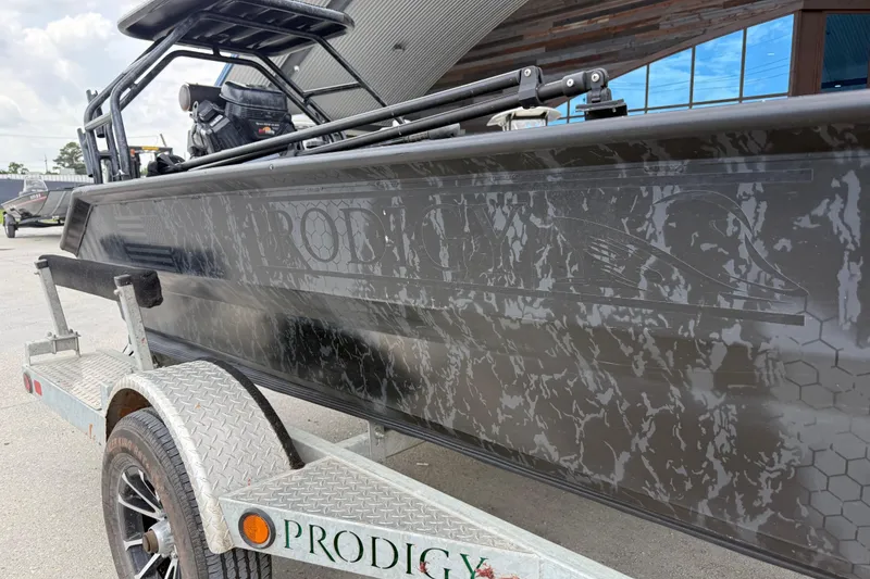 Slide: The Image of 2024 Prodigy 17 boat on trailer, featuring sleek design and camouflage pattern. - 16