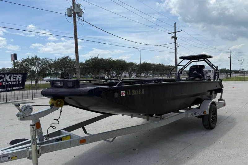 Slide: The Image of 2024 Prodigy 17 boat on trailer, parked outdoors under a cloudy sky. - 7