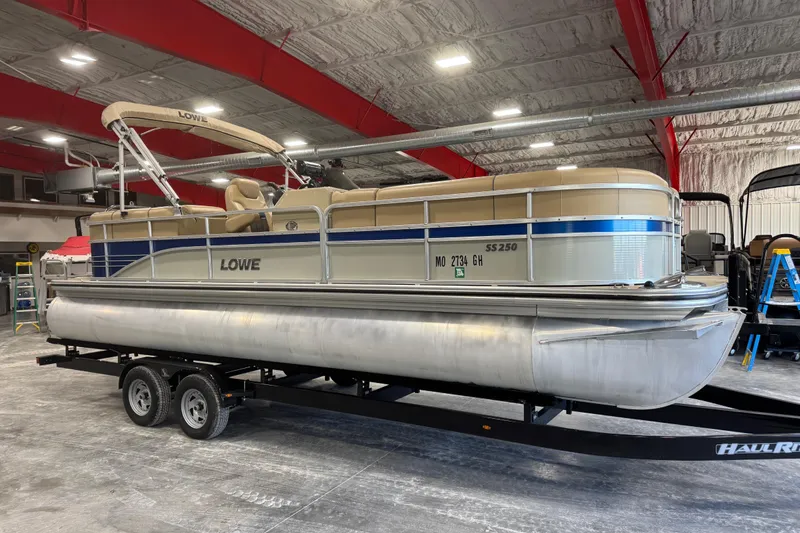The Image of 2017 Lowe SS 250 pontoon boat on trailer in indoor storage facility. - 1