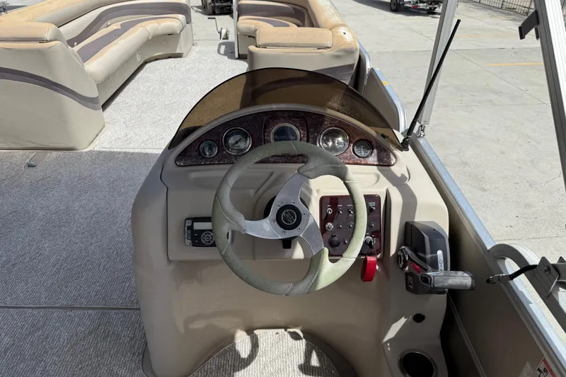 Slide: The Image of Steering console of a 2012 South Bay 522 CR pontoon boat with beige seating. - 13