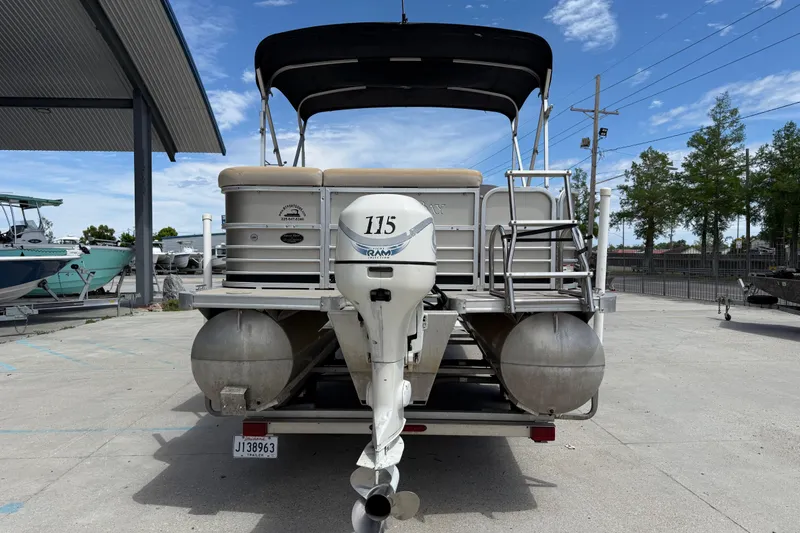 Slide: The Image of 2012 South Bay 522 CR pontoon boat with outboard motor, parked outdoors under blue sky. - 4