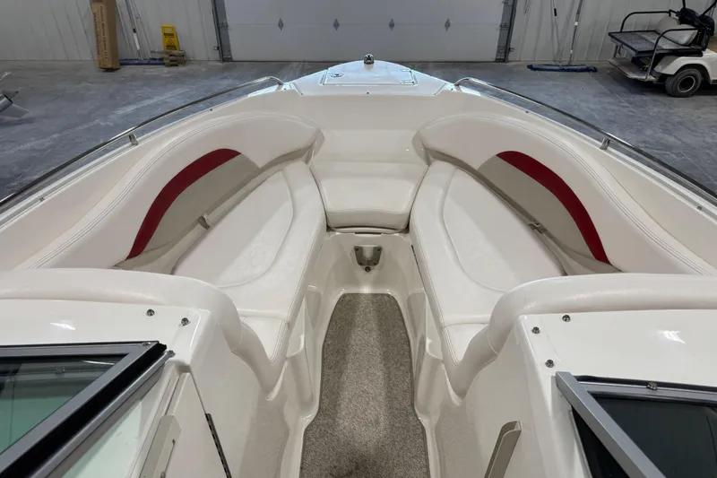 Slide: The Image of 2010 Chaparral 256 SSX boat interior with white seating and red accents in a garage. - 11