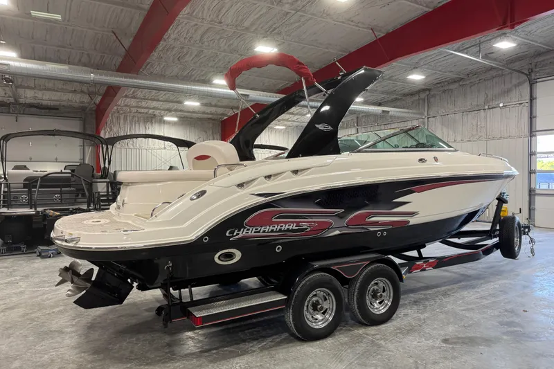Slide: The Image of 2010 Chaparral 256 SSX boat in a garage, featuring sleek design and dual-axle trailer. - 4