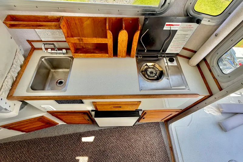 Slide: The Image of Compact 2006 Osprey Legend RV kitchen with sink, stove, and wooden cabinetry. - 20