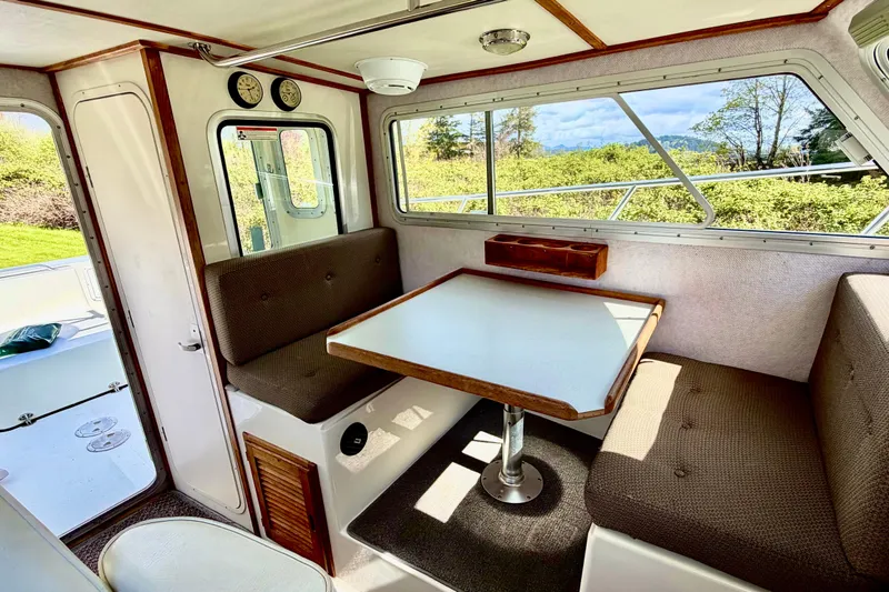 Slide: The Image of Interior of 2006 Osprey Legend boat with seating and table, surrounded by windows. - 14
