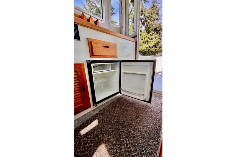 Slide: The Image of Open mini fridge inside 2006 Osprey Legend boat, with wooden cabinetry and carpeted floor. - 19