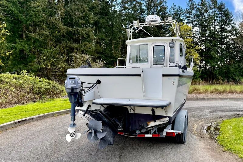 Slide: The Image of 2006 Osprey Legend boat on trailer, surrounded by lush greenery and trees. - 2