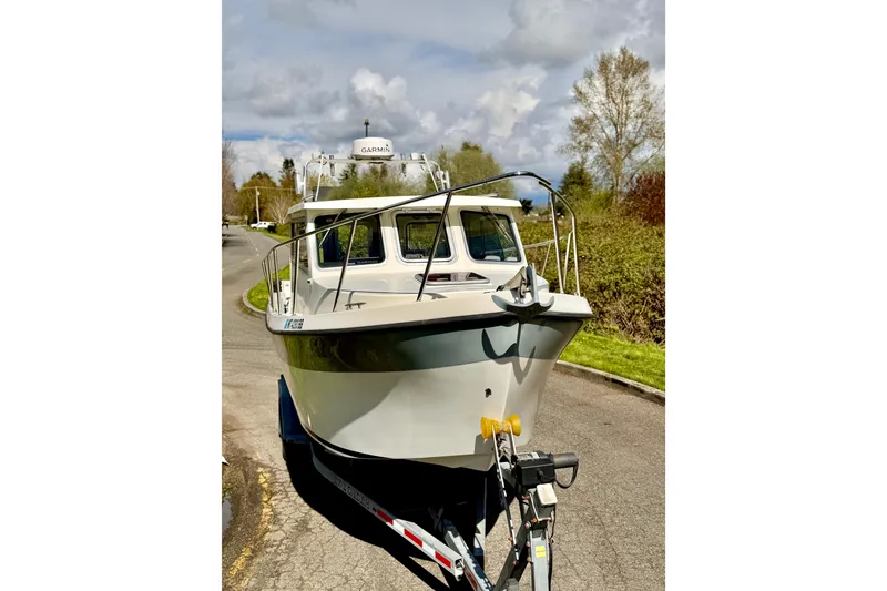 Slide: The Image of 2006 Osprey Legend boat on trailer, parked on a sunny road with trees in background. - 26